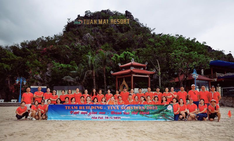 Đoàn Tina Services cầm băng rôn trên bãi biển trong chuyến nghỉ mát
