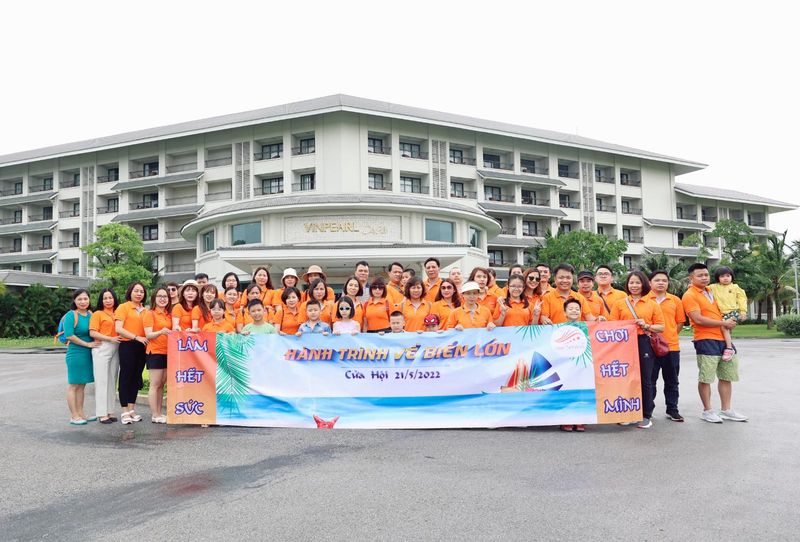 Đoàn Tina Services cầm băng rôn trước khách sạn trong chuyến nghỉ mát