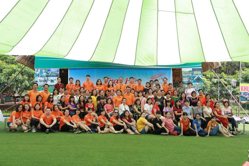 Tập thể Tina Services mặc áo cam chụp ảnh chung dưới lều trại hè