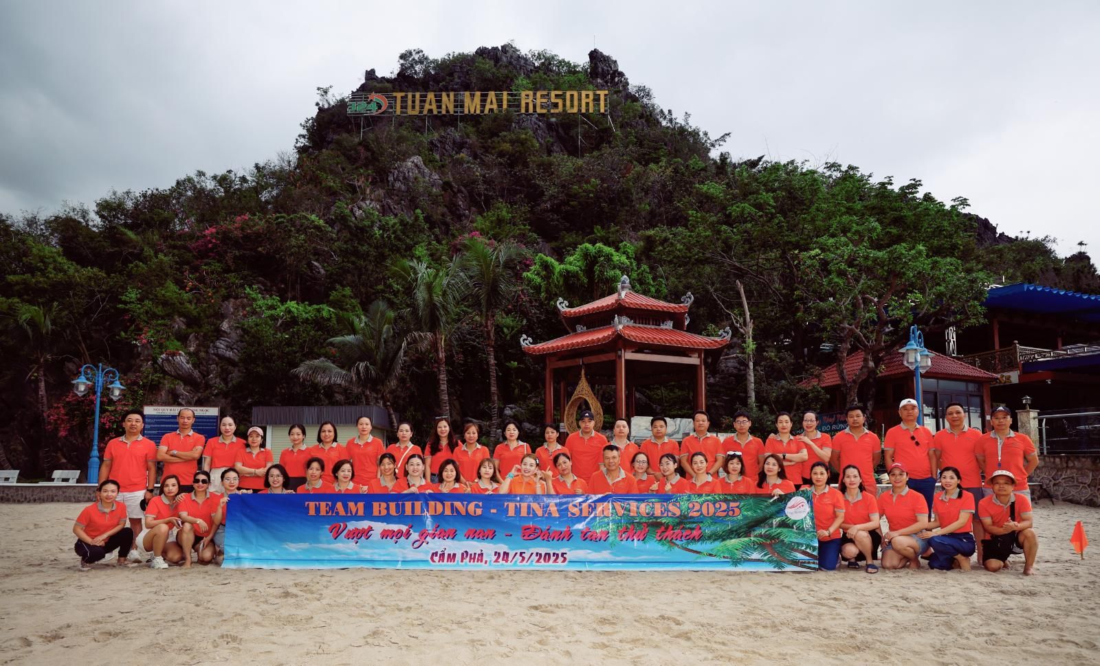 Tập thể Tina Services mặc áo cam trong chuyến team building năm 2025 trên bãi biển
