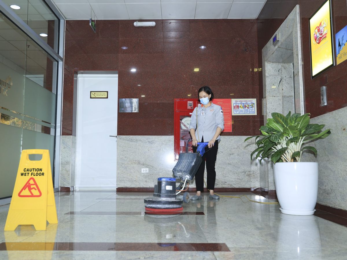 Nhân viên đánh bóng sàn đá sảnh toà nhà bằng máy chà sàn đơn