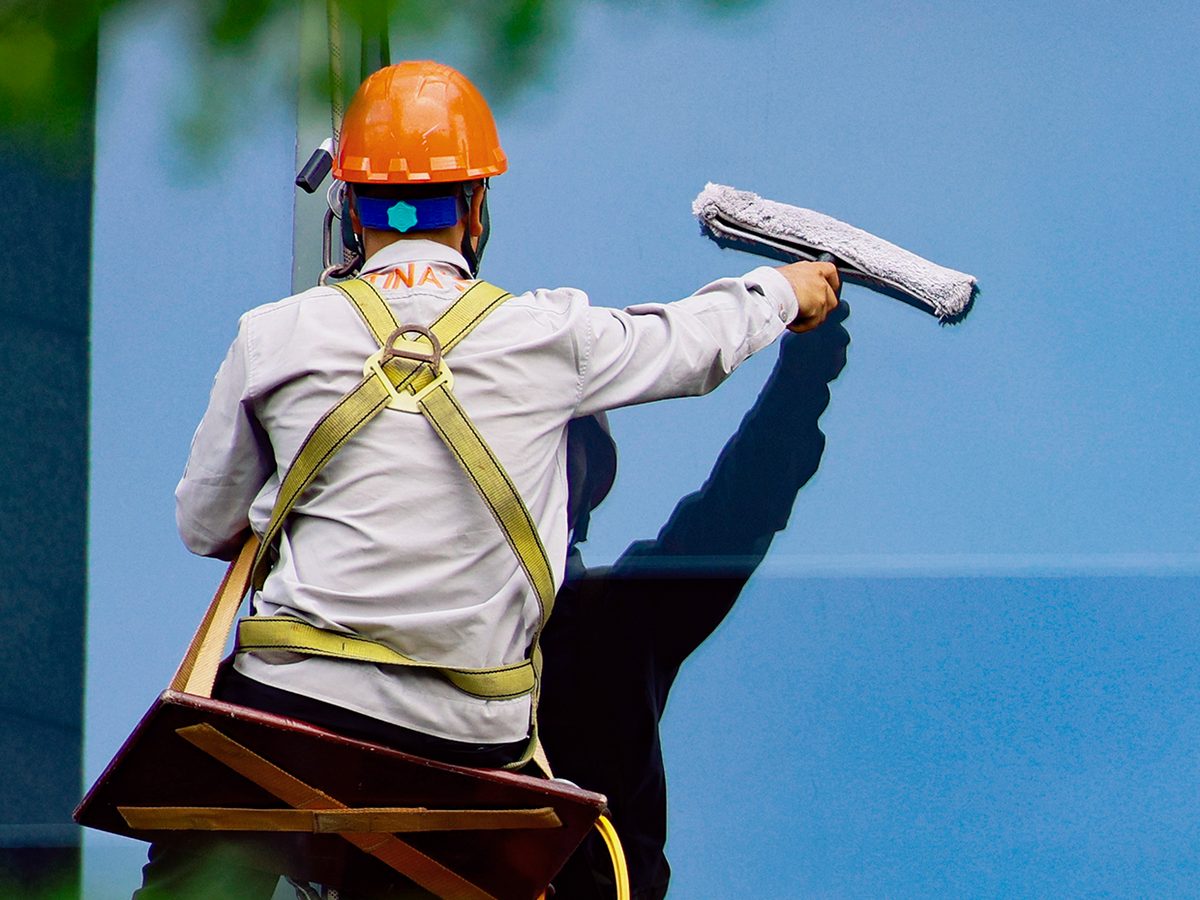 Nhân viên Tina Services đu dây làm sạch kính mặt ngoài toà nhà