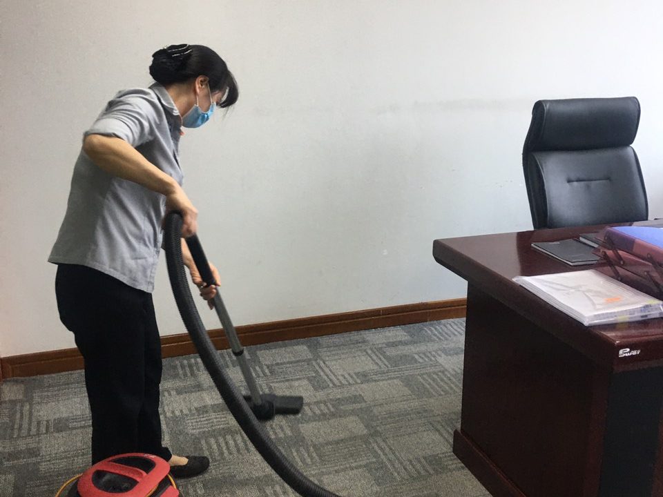 Nhân viên Tina Services hút bụi thảm trong phòng làm việc
