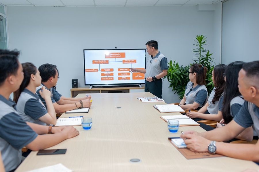Cán bộ Tina Services trong một buổi họp nội bộ, người trình bày giới thiệu sơ đồ tổ chức trên màn hình