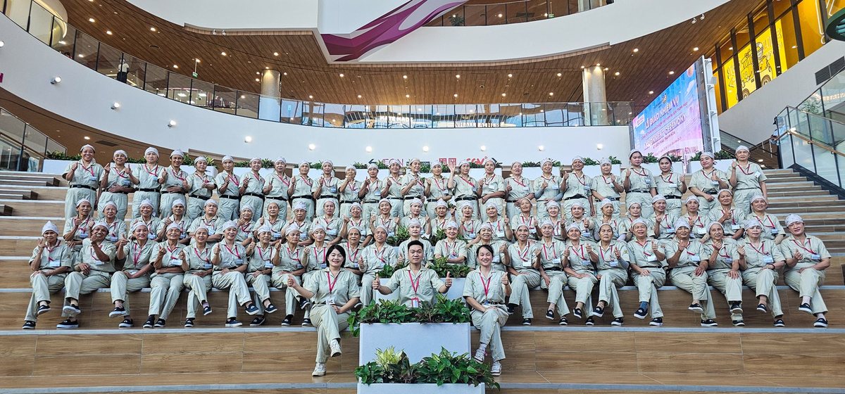 Đội ngũ nhân viên Tina Services mặc đồng phục ngồi trên bậc thang sảnh AEON Mall Thanh Hóa